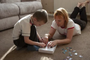 Kind sitzt ruhig auf dem Boden und beschäftigt sich mit einem Puzzle